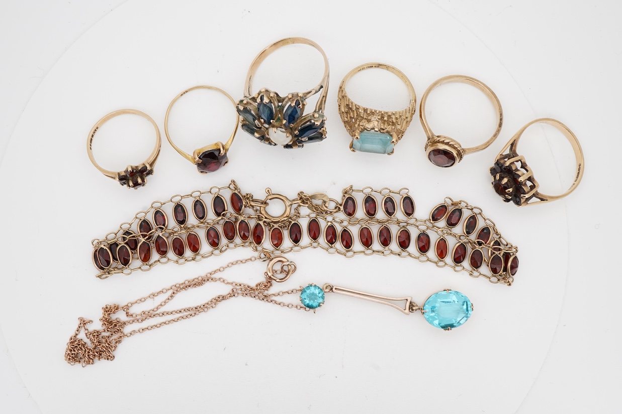 A group of jewels, comprising: two garnet cluster rings; a garnet bracelet; and a blue topaz ring, each mounted in 9ct gold, ring sizes H-M1/2, combined gross weight 13 grams; together with a marquise-shaped sapphire and